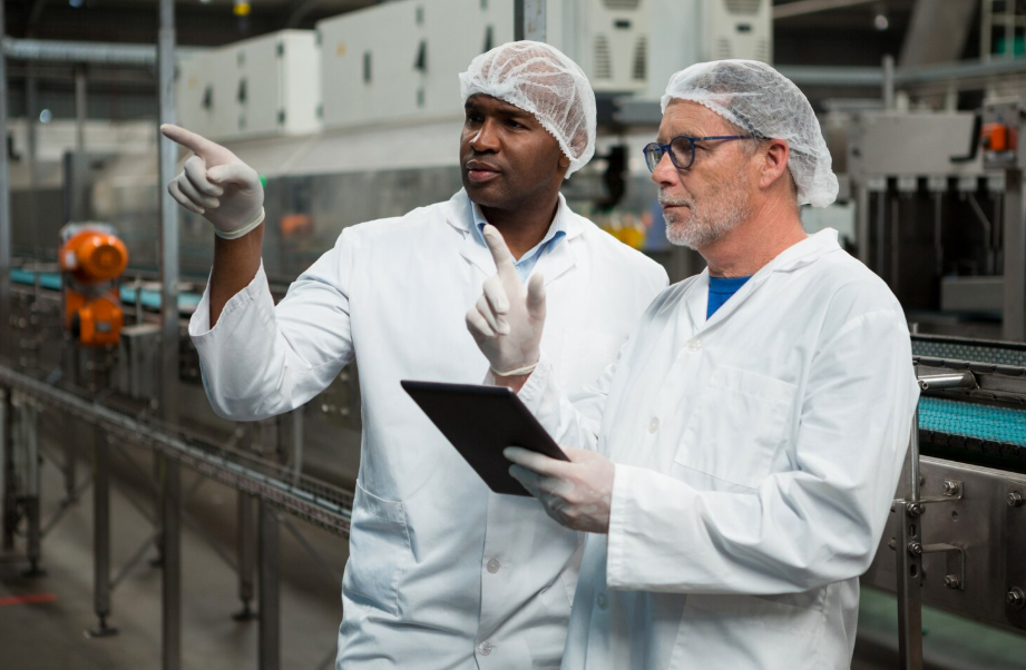 Auditores de seguridad alimentaria revisando procesos de producción en planta conforme a la norma IFS Food.