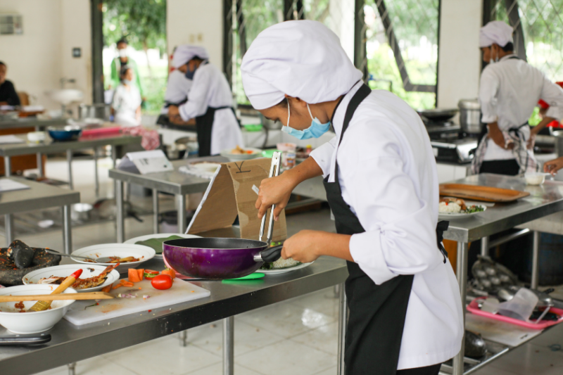 Estudiante de gastronomía preparando alimentos en una cocina profesional siguiendo estándares de seguridad alimentaria BRCGS Food Safety