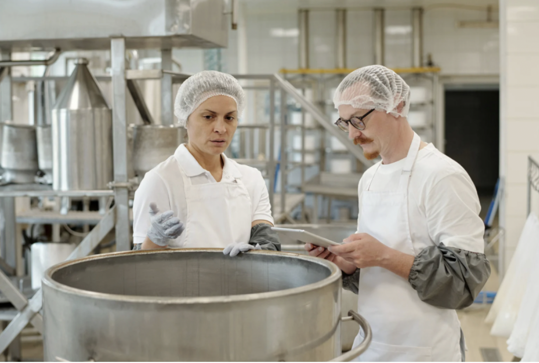 Trabajadores de la industria alimentaria revisando procesos de producción para cumplir con la ley de desperdicio alimentario y mejorar la gestión de excedentes.