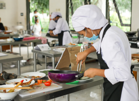 Estudiante de gastronomía preparando alimentos en una cocina profesional siguiendo estándares de seguridad alimentaria BRCGS Food Safety